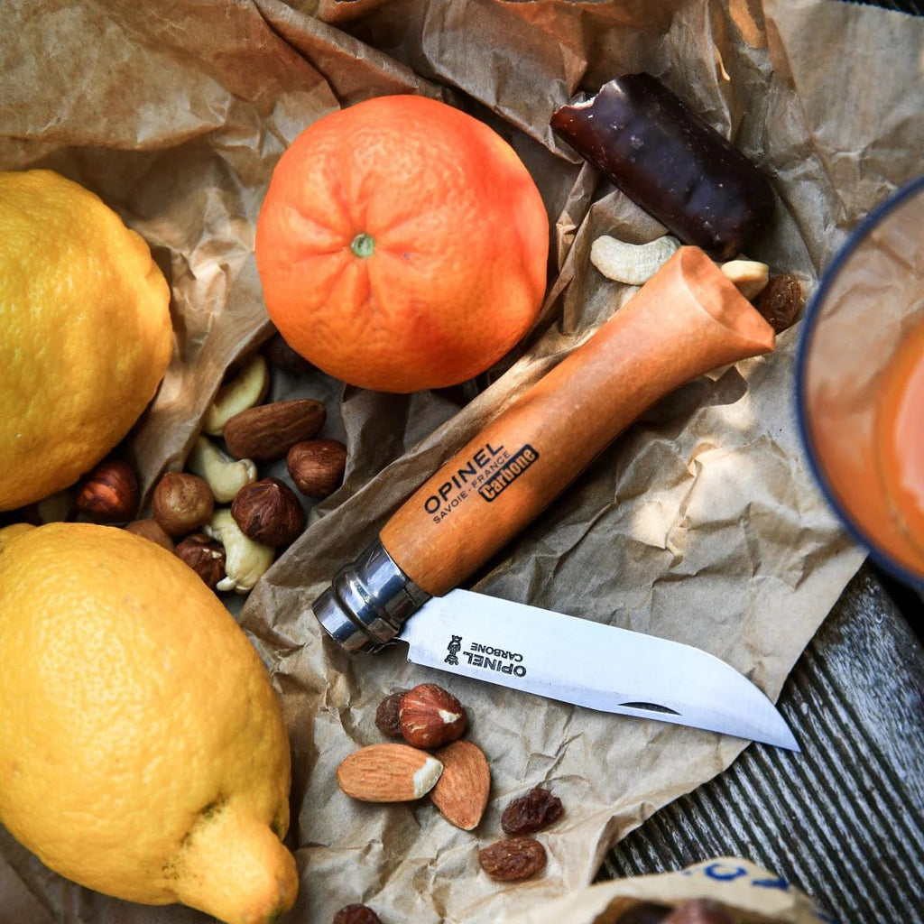 Cuchillo Opinel N°10 Carbon Steel - vista 3, en uso, junto a frutas y frutos secos