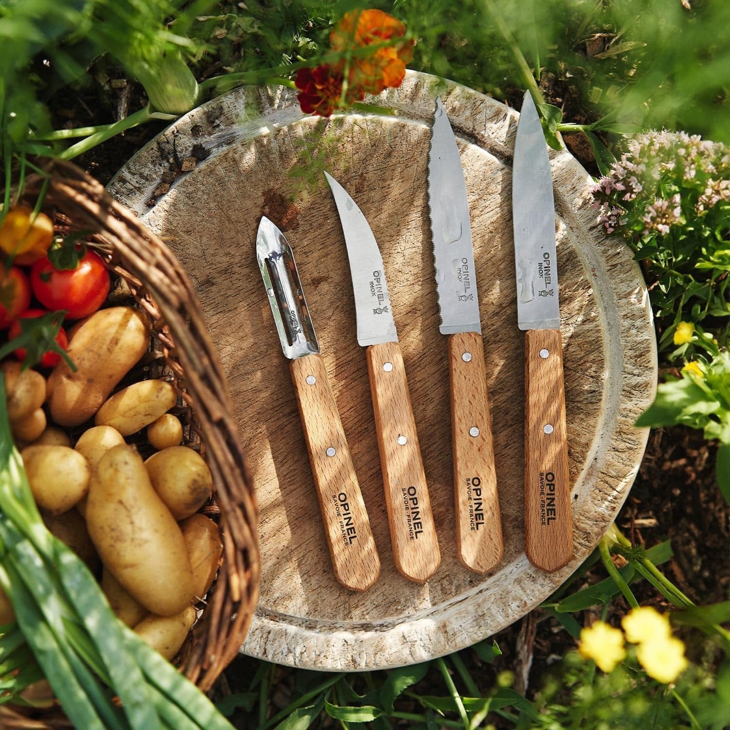 Set Les Essentiels Opinel - vista 2, los 4 cuchillos sobre tabla con verduras