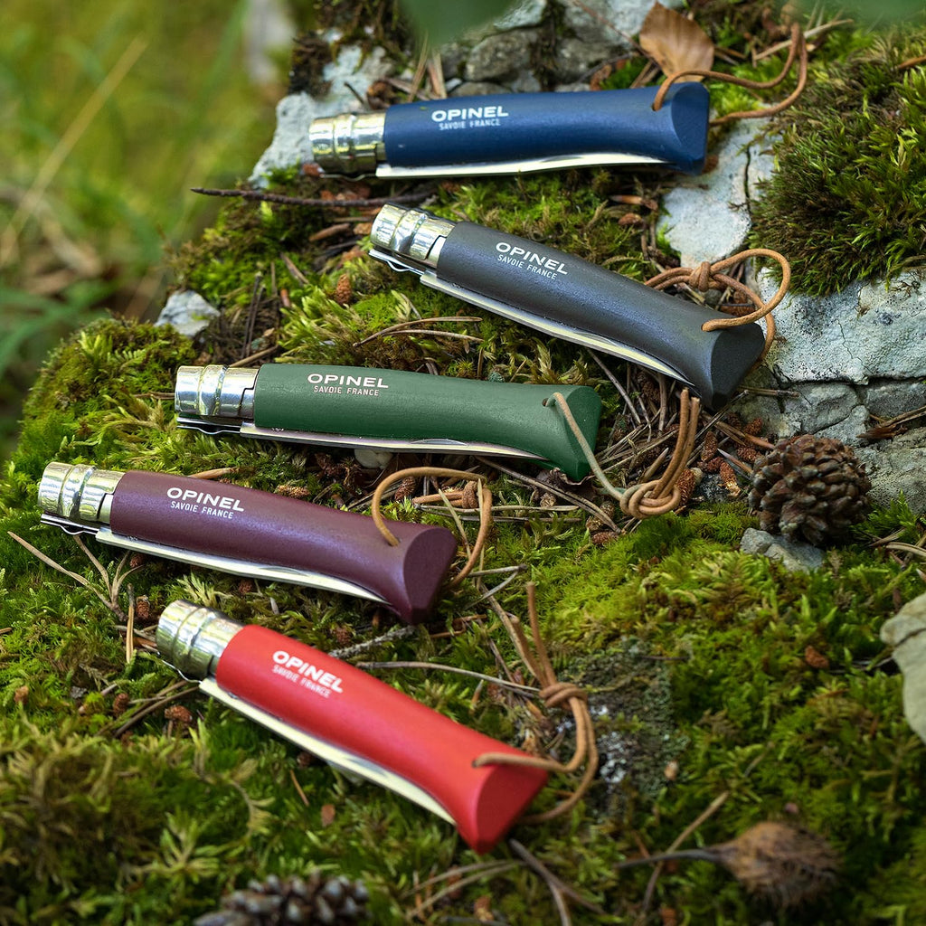 Cuchillo Opinel N°8 Trekking rojo con funda - vista 5, varios cuchillos de colores sobre musgo, estilo de vida