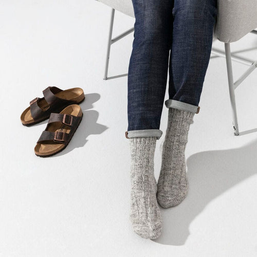 Calcetines Birkenstock Cotton Twist Light Gray, puesto por modelo, sentado, con el calzado de fondo, en uso, imagen de estilo de vida