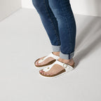Sandalias Birkenstock Gizeh Patent White, calzado por modelo femenino, primer plano del pie