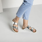 Sandalias Birkenstock Arizona Metallic Silver, calzado por modelo femenino, primer plano de piernas y pies