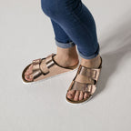 Sandalias Birkenstock Arizona Metallic Copper, calzado por modelo femenino, primer plano del tobillo