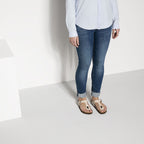 Sandalias Birkenstock Gizeh Graceful Pearl White, calzado por modelo femenino, primer plano de piernas y pies
